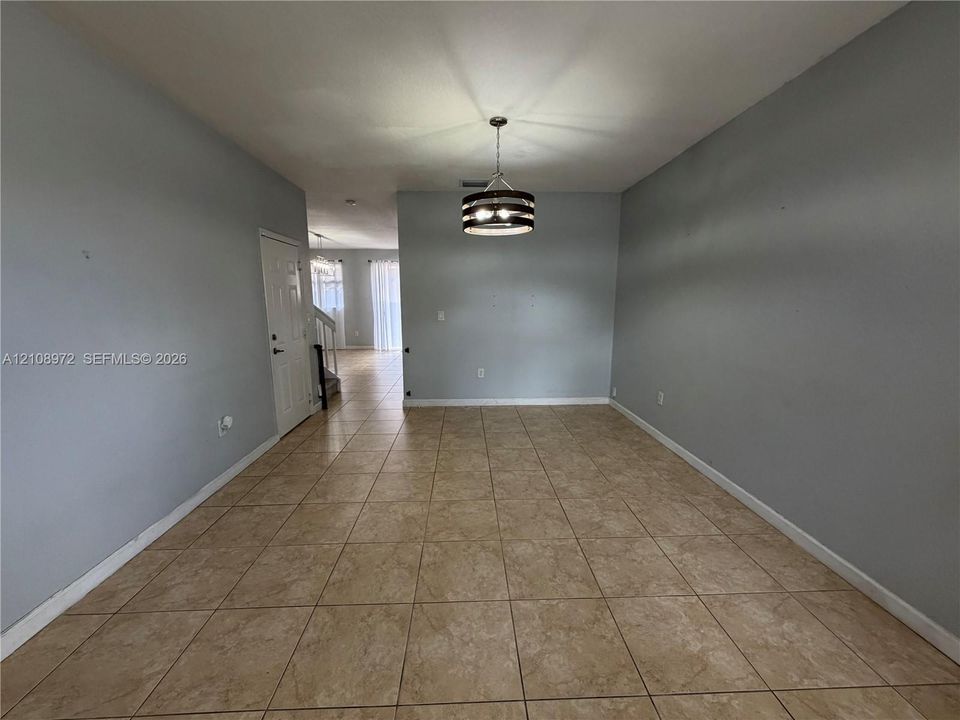 Neutral-toned interior featuring ceramic tile flooring, a drum-style pendant light fixture, and a multi-panel door