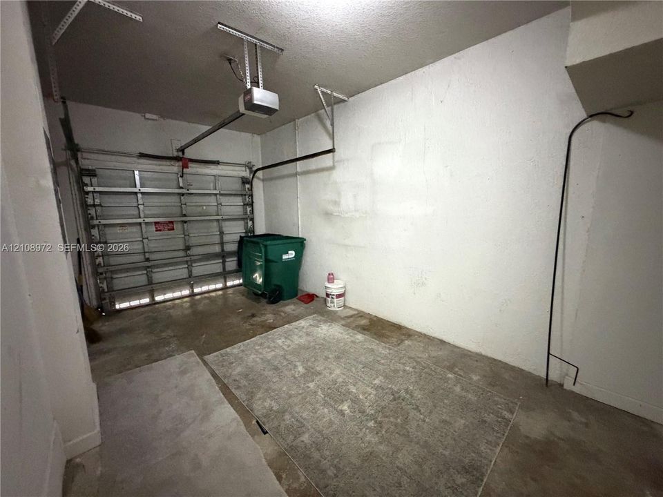 Enclosed garage space featuring a metal sectional door and automated overhead door opener