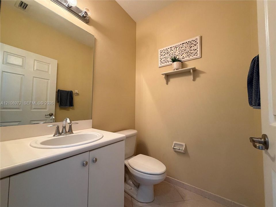 Bathroom featuring a vanity cabinet with a solid surface countertop, an integrated oval sink, a wall-mounted mirror, and a polished chrome faucet