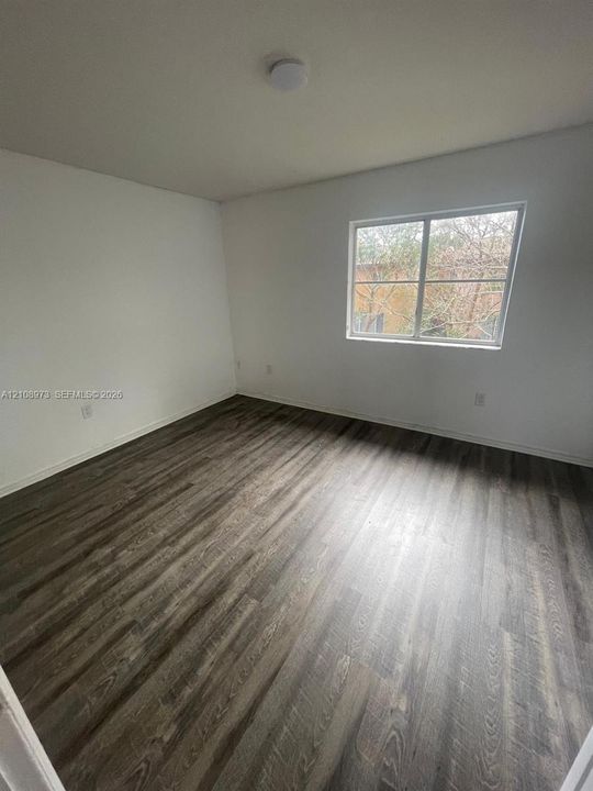 Interior room featuring wood-finish flooring, white walls, and a single-pane window