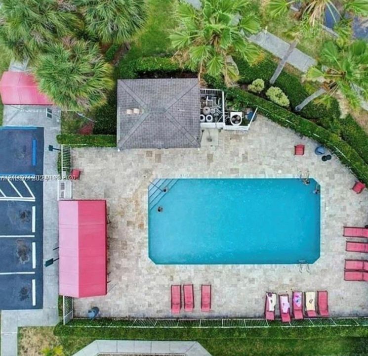 Outdoor recreation area featuring a swimming pool, stone-paver decking, a covered gazebo, and perimeter landscaping