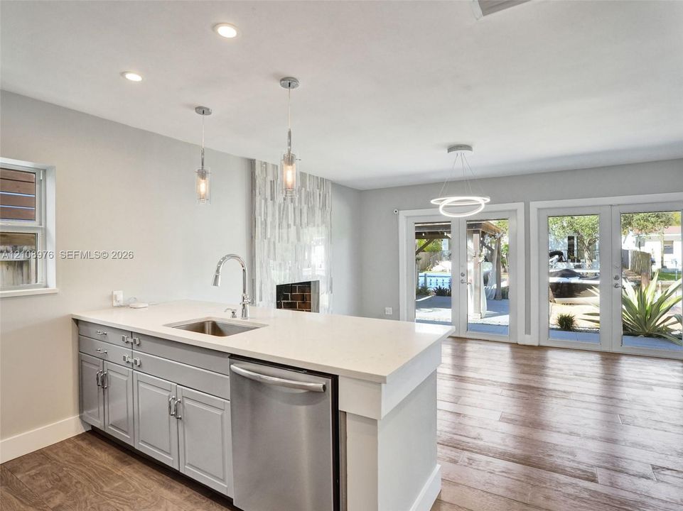 Kitchen island featuring light-toned cabinetry, a stone-finish countertop, stainless steel undermount sink, and recessed lighting