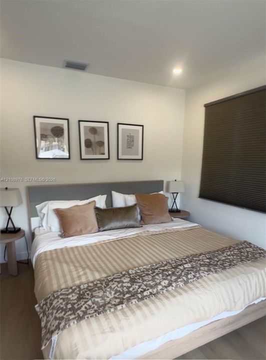 Neutral walls, wood-finish flooring, and a pleated window shade
