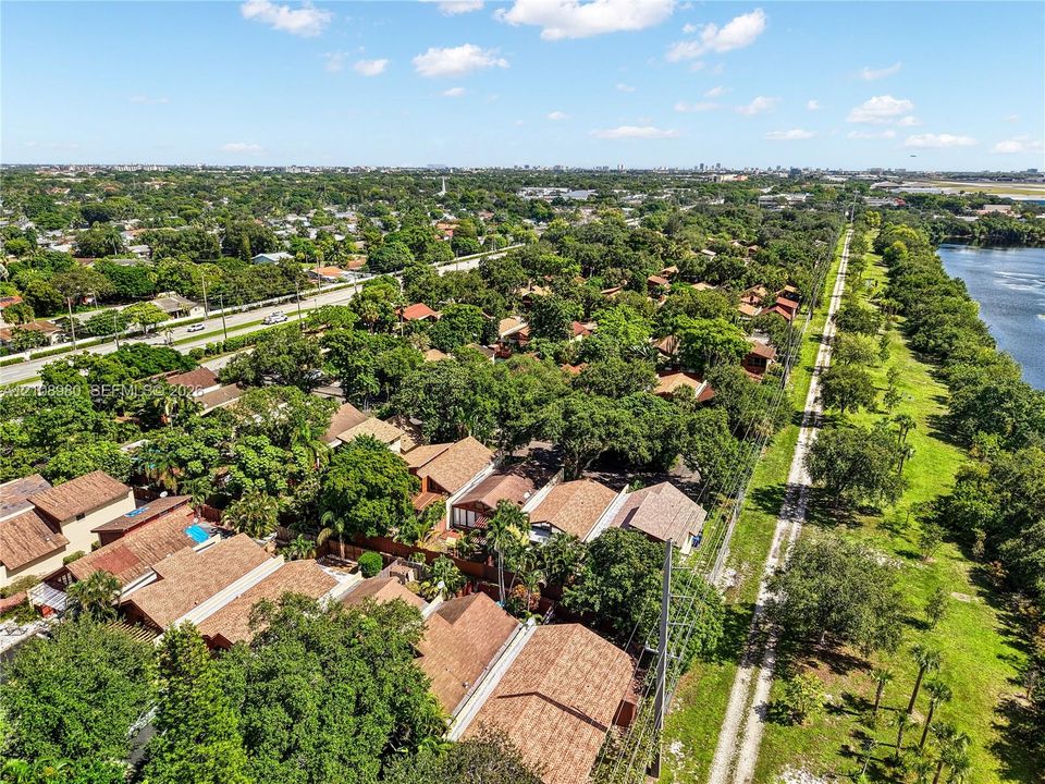 Aerial perspective of residential properties featuring shingle-style roofing, dense mature tree canopy, and direct positioning along a water feature