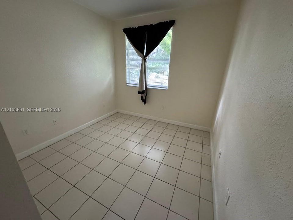 Neutral interior room featuring ceramic tile flooring, textured walls, and a single-pane window