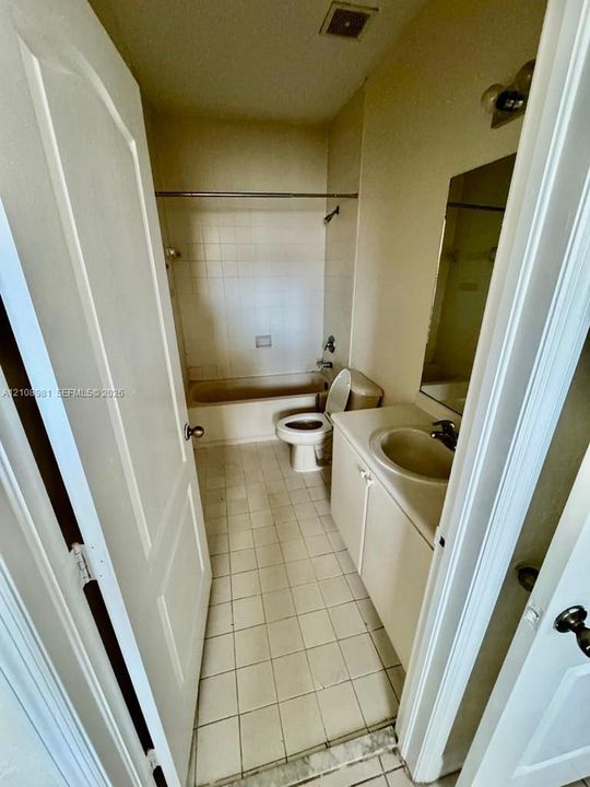 Bathroom featuring a tiled floor, shower-tub combination with white wall tile, built-in vanity with an integrated sink, wall-mounted mirror, and overhead lighting fixture