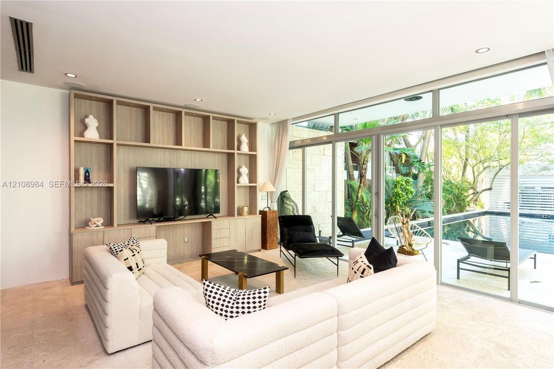 Floor-to-ceiling sliding glass doors, custom wood-finish floor-to-ceiling built-in cabinetry, recessed lighting, and stone flooring