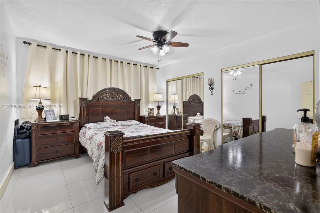 Ceramic tile flooring, dual mirrored sliding-door closets, and an integrated ceiling fan with light fixture