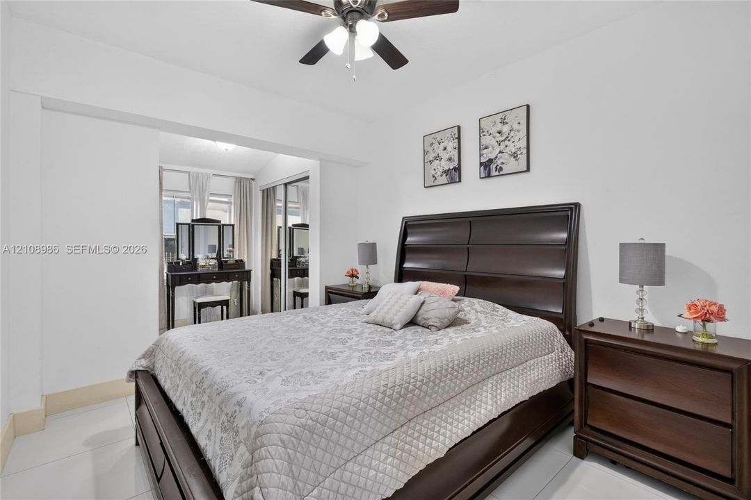 Room featuring large-format tile flooring, built-in dual-paneled sliding closet doors, and a ceiling fan with integrated lighting
