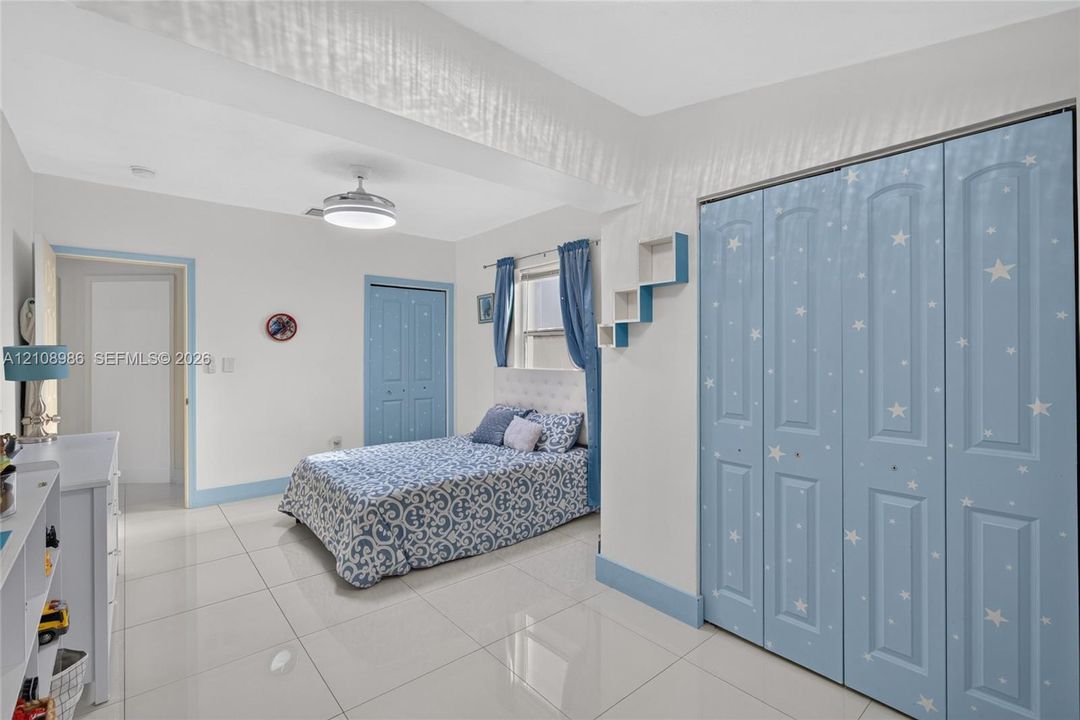 Large-format tile flooring, recessed ceiling lighting with integrated fan, and built-in wall shelving