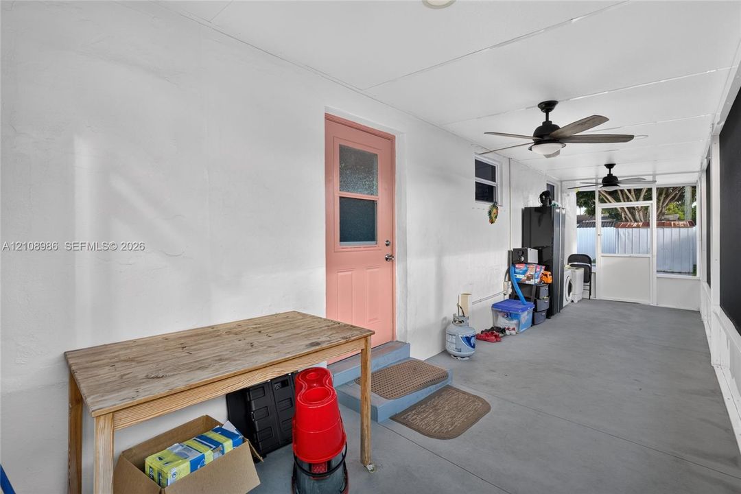 Covered porch featuring painted concrete flooring, two ceiling fans, and a solid-core exterior door with an integrated window