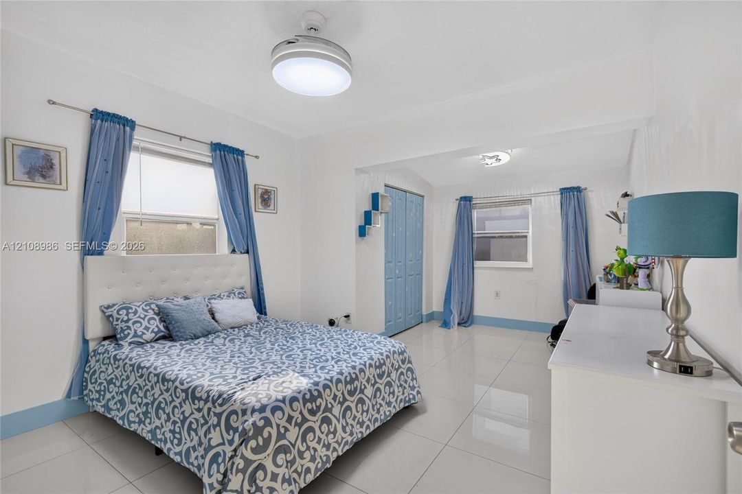 Spacious room featuring glossy tile flooring, dual windows, integrated ceiling lighting, and built-in bifold closet doors