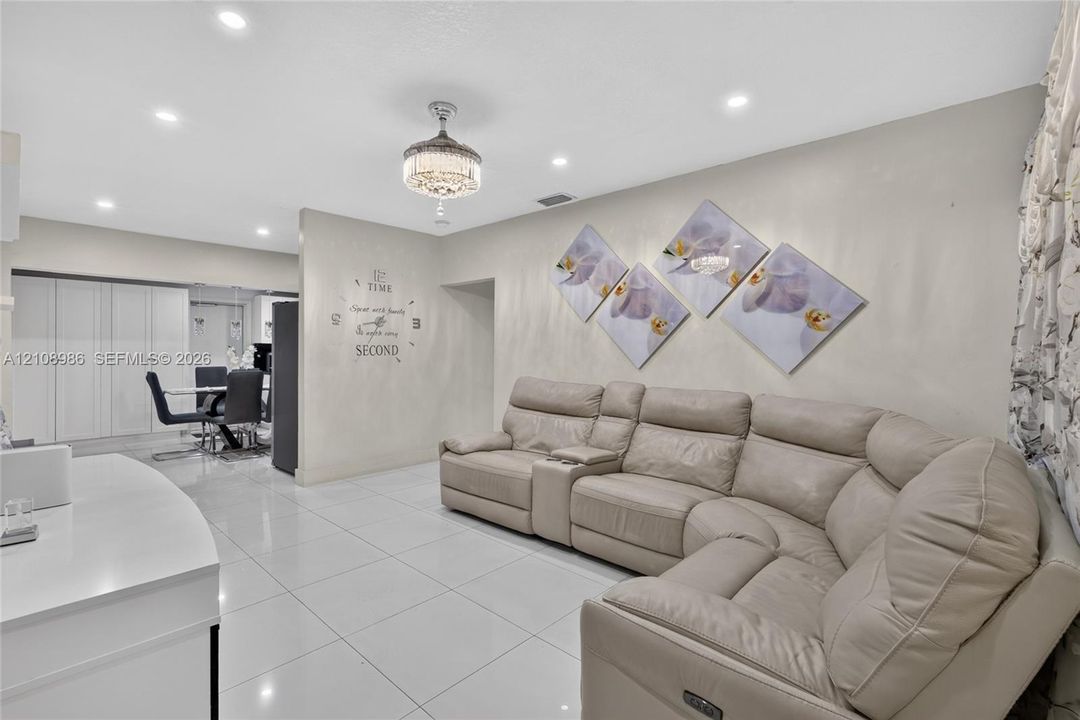 Large-format tile flooring, recessed ceiling lighting, and a decorative crystal-style chandelier