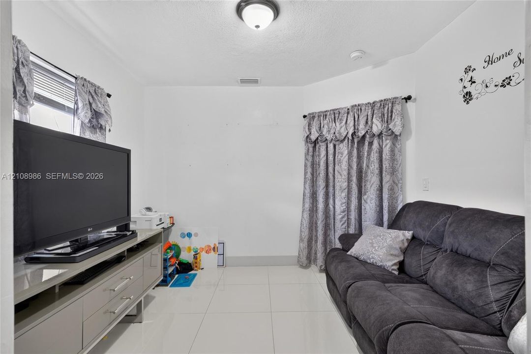 Interior space featuring large-format tile flooring, a multi-faceted wall design, and a flush-mount ceiling light fixture