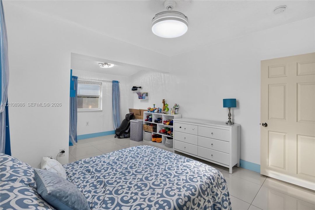 Neutral-toned tile flooring, six-panel interior door, and flush-mount ceiling light fixture with integrated fan
