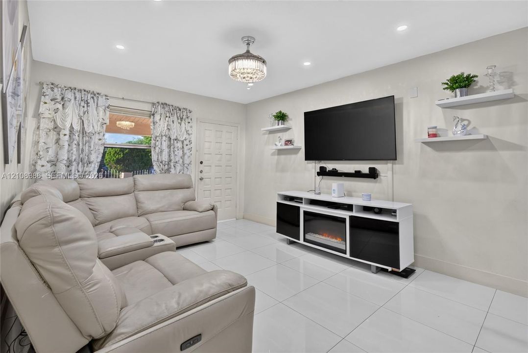 Large-format tile flooring, recessed ceiling lighting, and a decorative crystal-style chandelier fixture