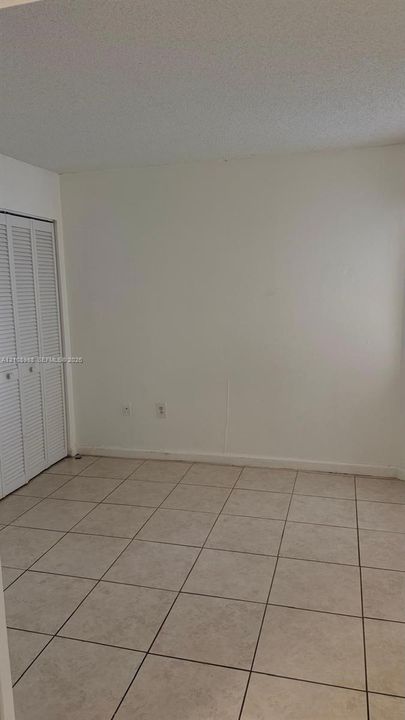 Neutral-toned tile flooring and white bi-fold closet doors