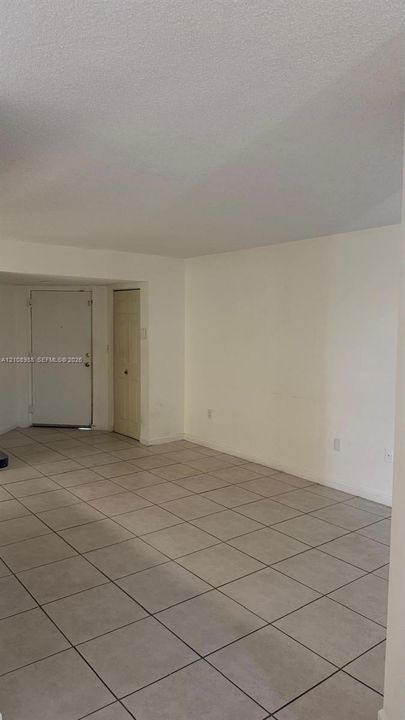 Neutral-toned tile flooring, solid-core entry door, and built-in closet with six-panel door