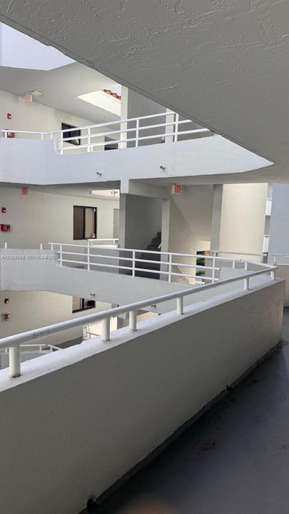 Multi-story structure featuring white concrete walkways, tiered levels, and metal railings