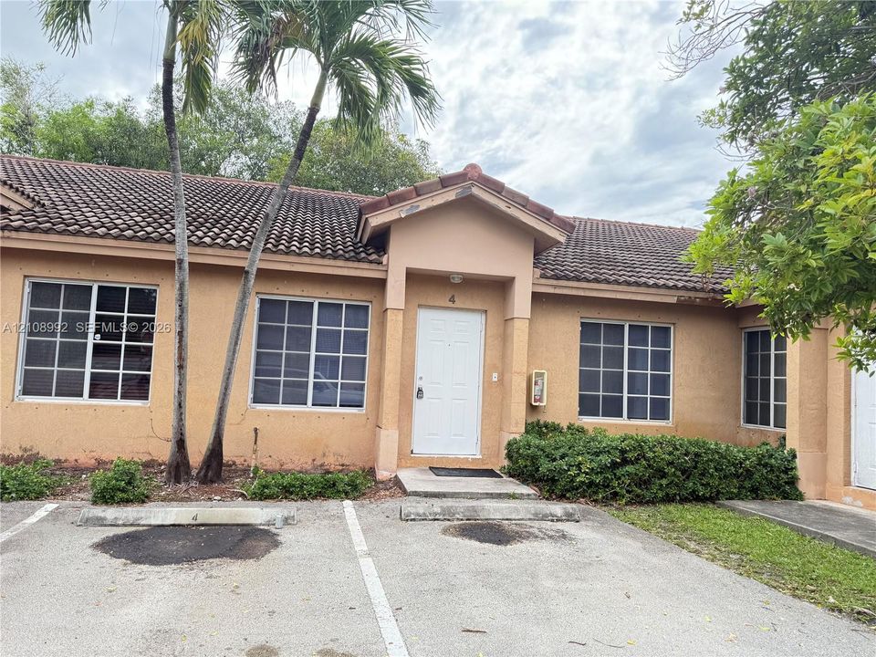 Stucco exterior with a tiled roof, multi-pane grid windows, and dedicated parking space