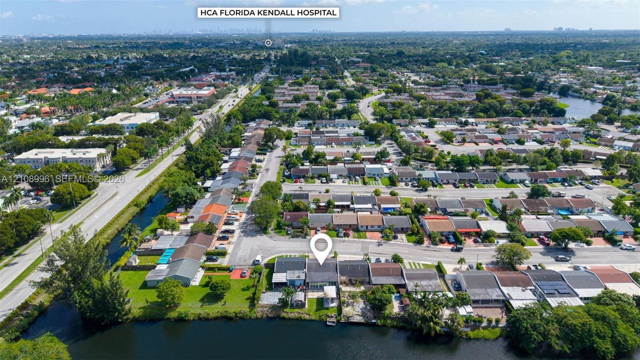 Aerial perspective of a residential property featuring a direct waterfront lot, private lawn area, and paved off-street parking
