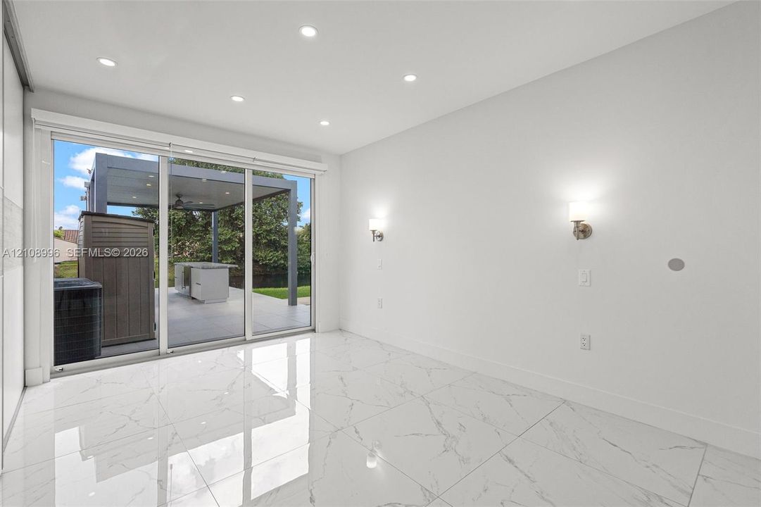 Large-format tile flooring with marble-style veining, recessed ceiling lighting, wall-mounted sconces, and sliding glass doors