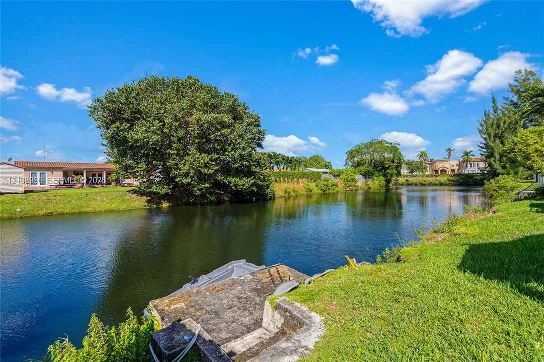 Waterfront parcel featuring a concrete bulkhead, private stair access to the canal, grassy lawn, and mature trees