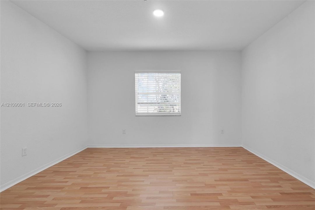 Neutral interior featuring wood-finish flooring, white walls, a single-pane window with horizontal blinds, and a recessed ceiling light