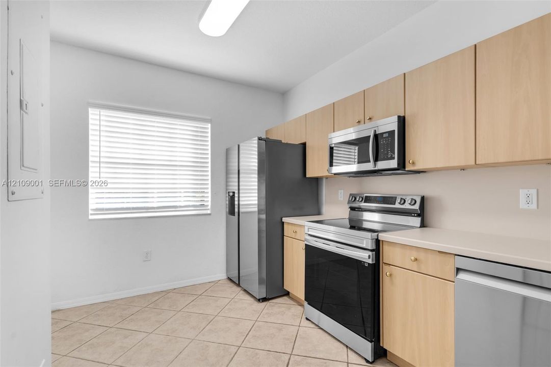 Kitchen featuring light-finish cabinetry, neutral-toned countertops, stainless steel appliances, and tiled flooring