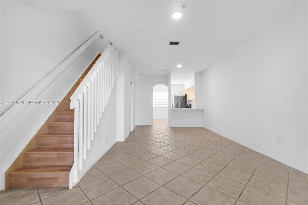 Ceramic tile flooring, staircase with wood-finish treads, white baluster railing, and recessed ceiling lighting