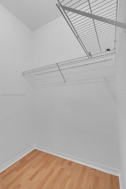 Storage area featuring wood-finish flooring and tiered white wire shelving
