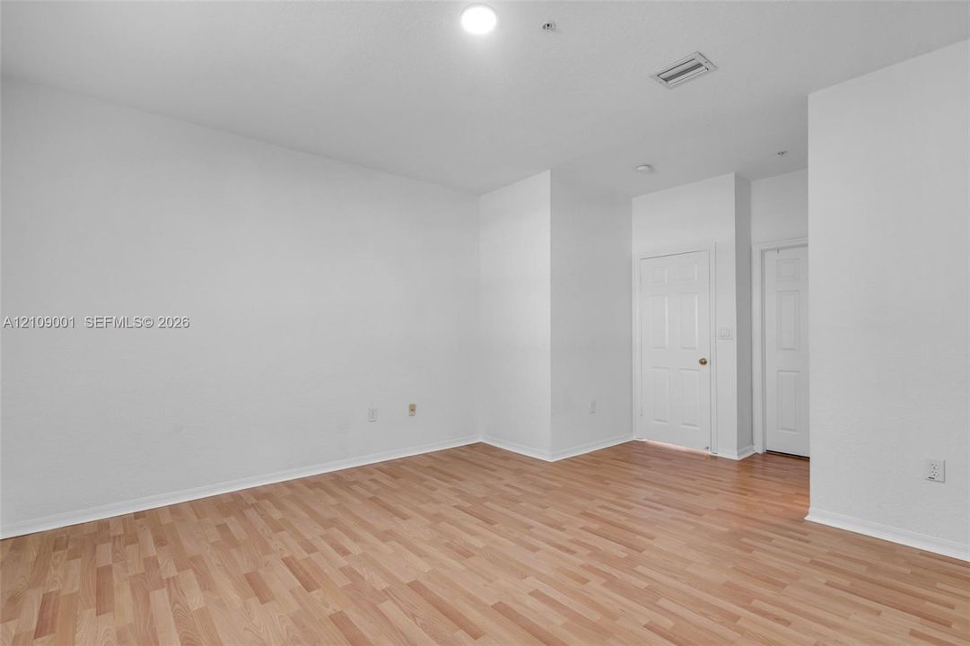 Interior space featuring wood-finish flooring, white walls, and two white panel doors