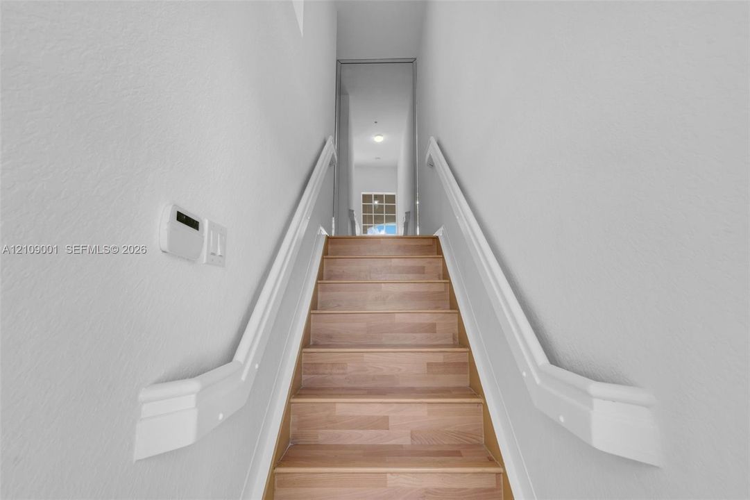 Staircase featuring wood-finish treads and dual white handrails