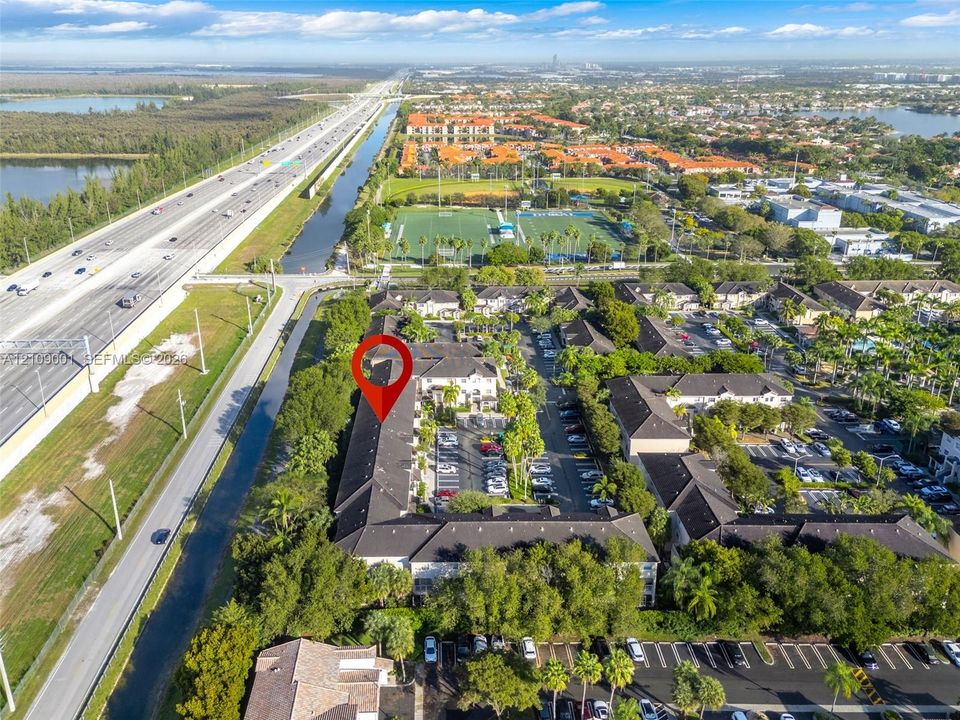 Aerial perspective of multi-family complex featuring tile roof construction, dedicated surface parking, and established landscaping