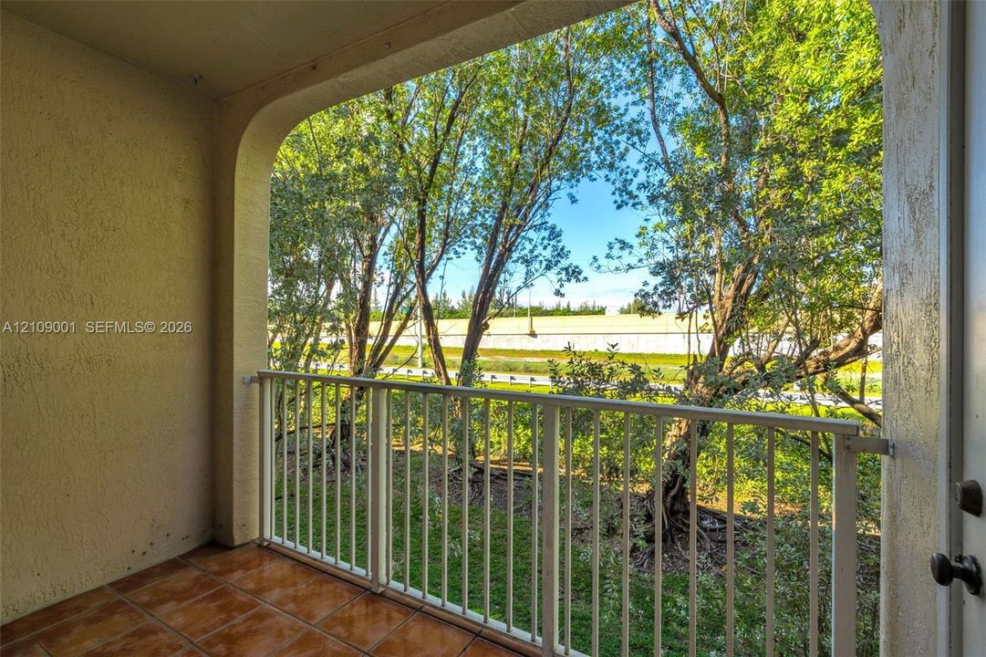 Covered balcony featuring tile flooring and a metal railing