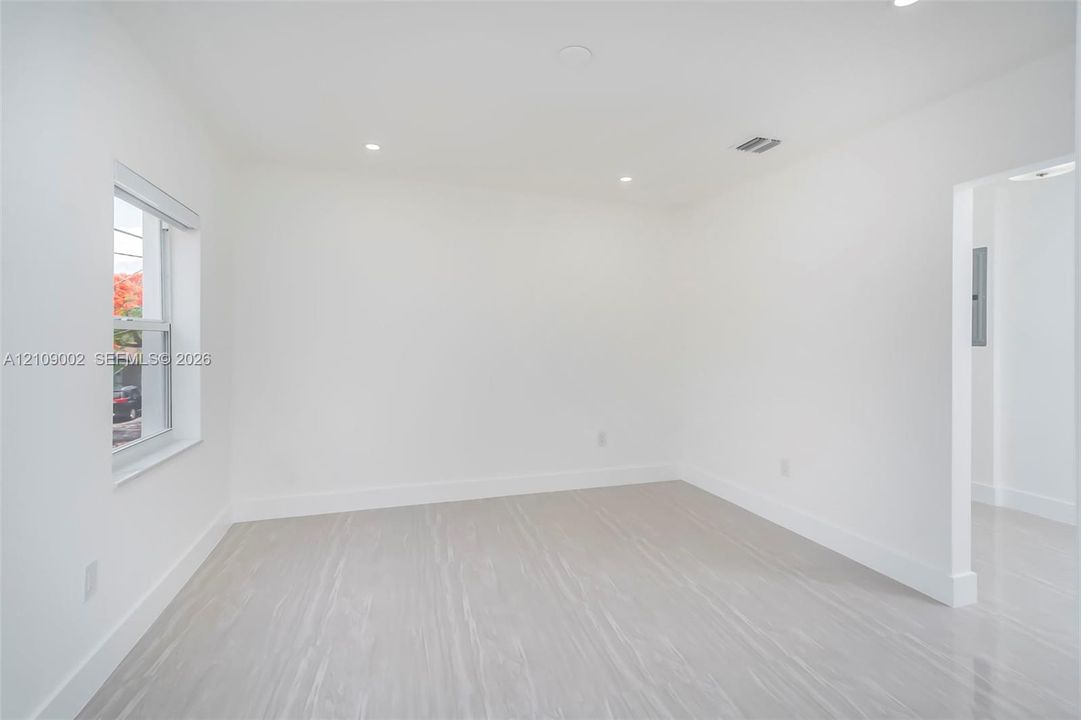 Neutral-toned interior space featuring light-colored wood-finish flooring, recessed lighting, and a single-pane window
