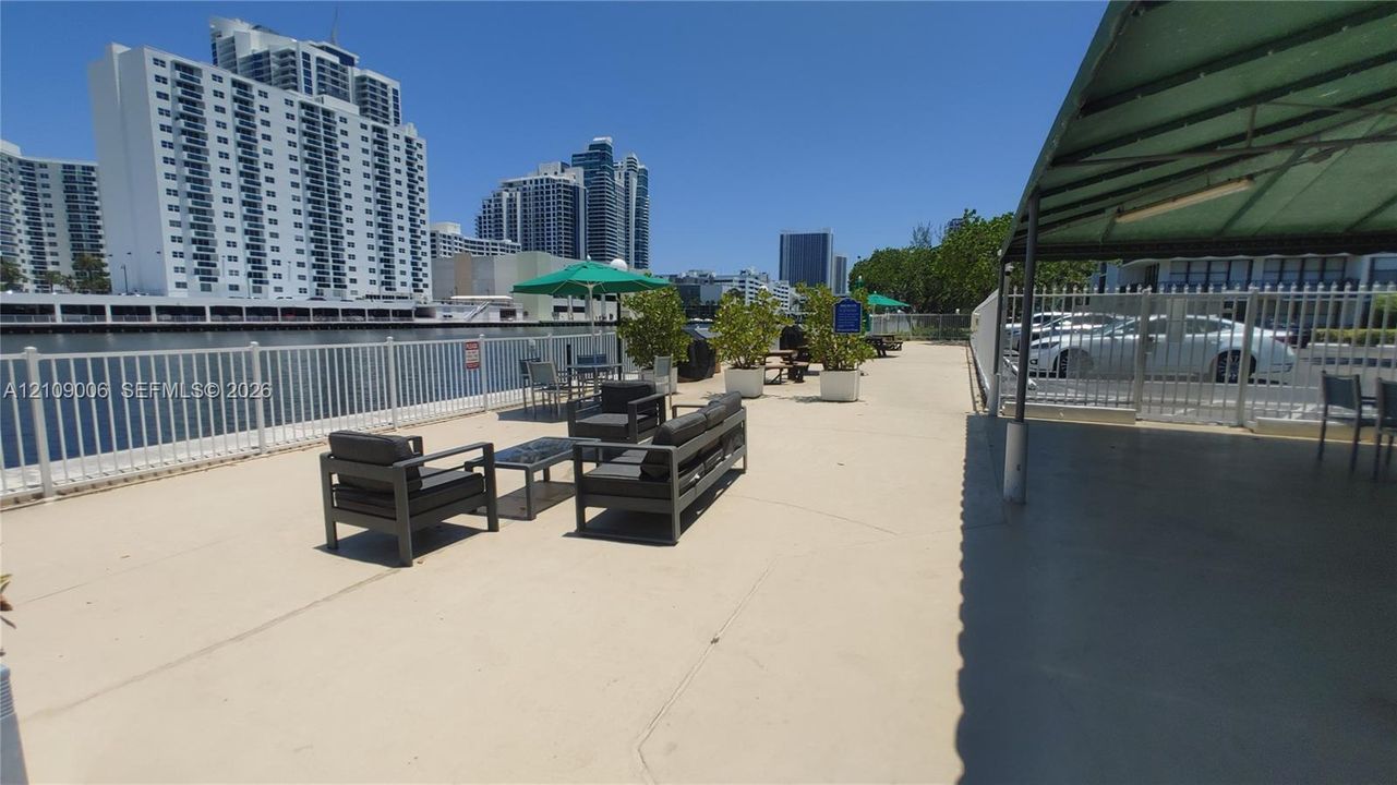 Waterfront terrace featuring a concrete deck, white metal perimeter fencing, and a covered pavilion