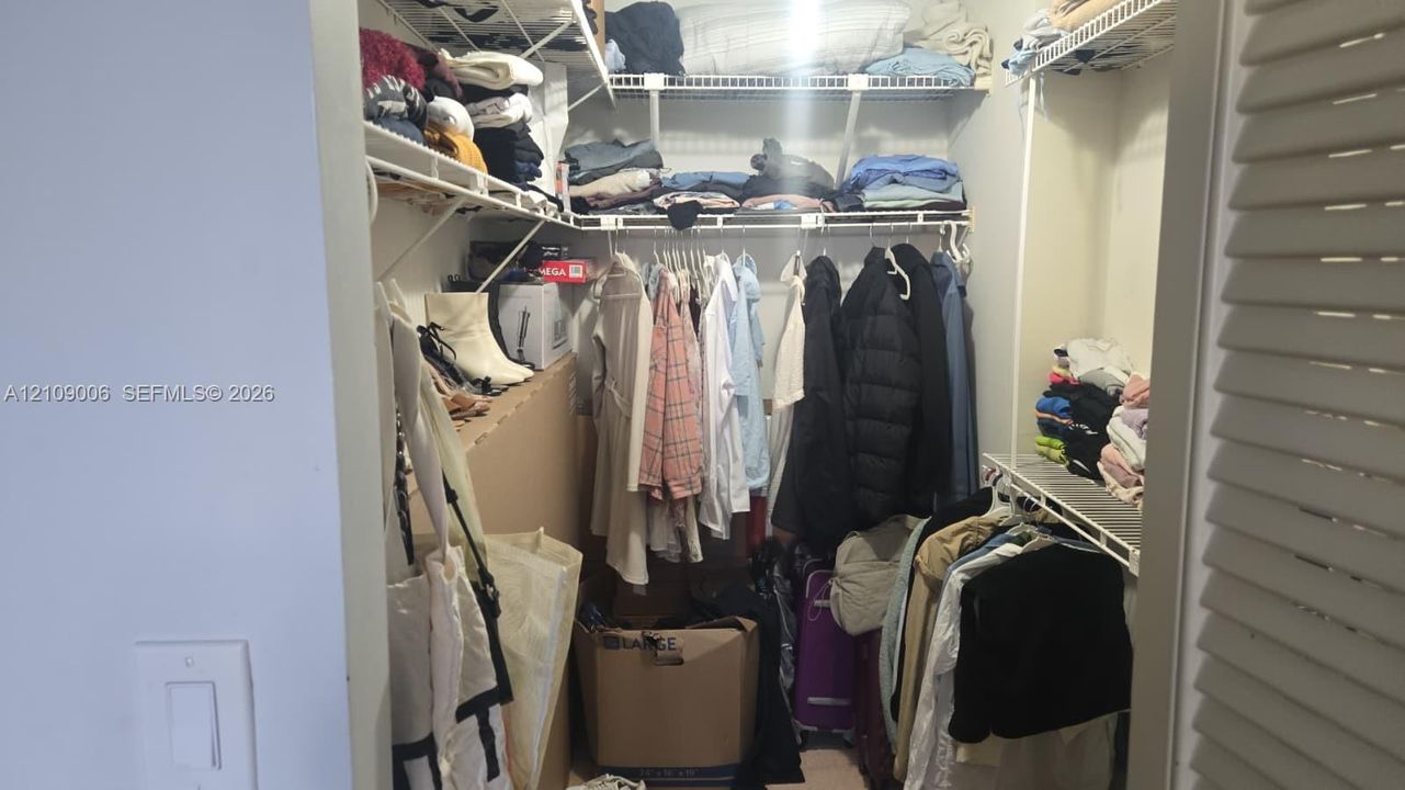 Walk-in closet featuring multi-tiered wire shelving and hanging rods