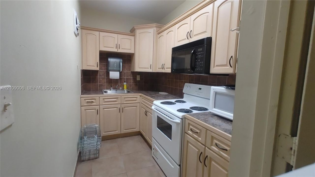 Kitchen featuring light-finish cabinetry, tile backsplash, built-in microwave, and tile flooring