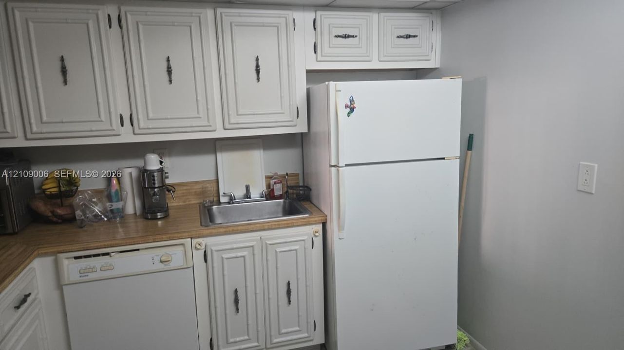 Kitchen area featuring white cabinetry, a top-mount stainless steel sink, a laminate countertop, and an integrated dishwasher