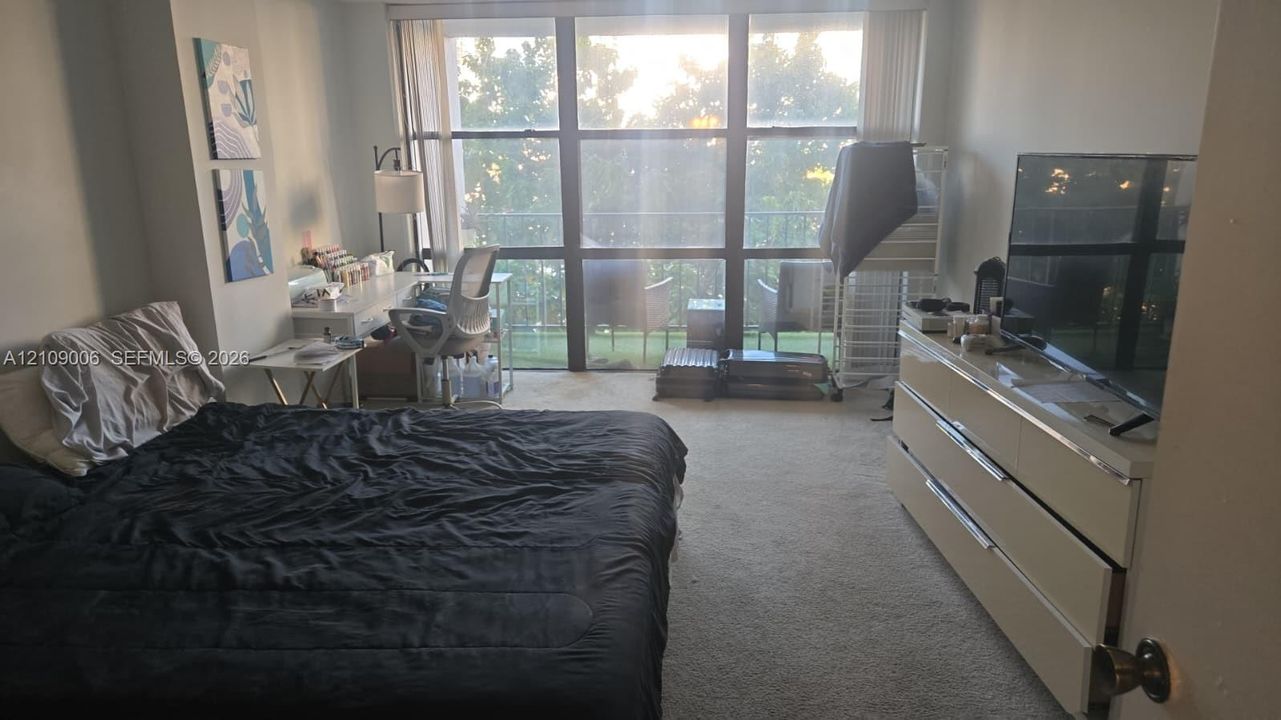 Floor-to-ceiling windows featuring balcony access and neutral carpeting