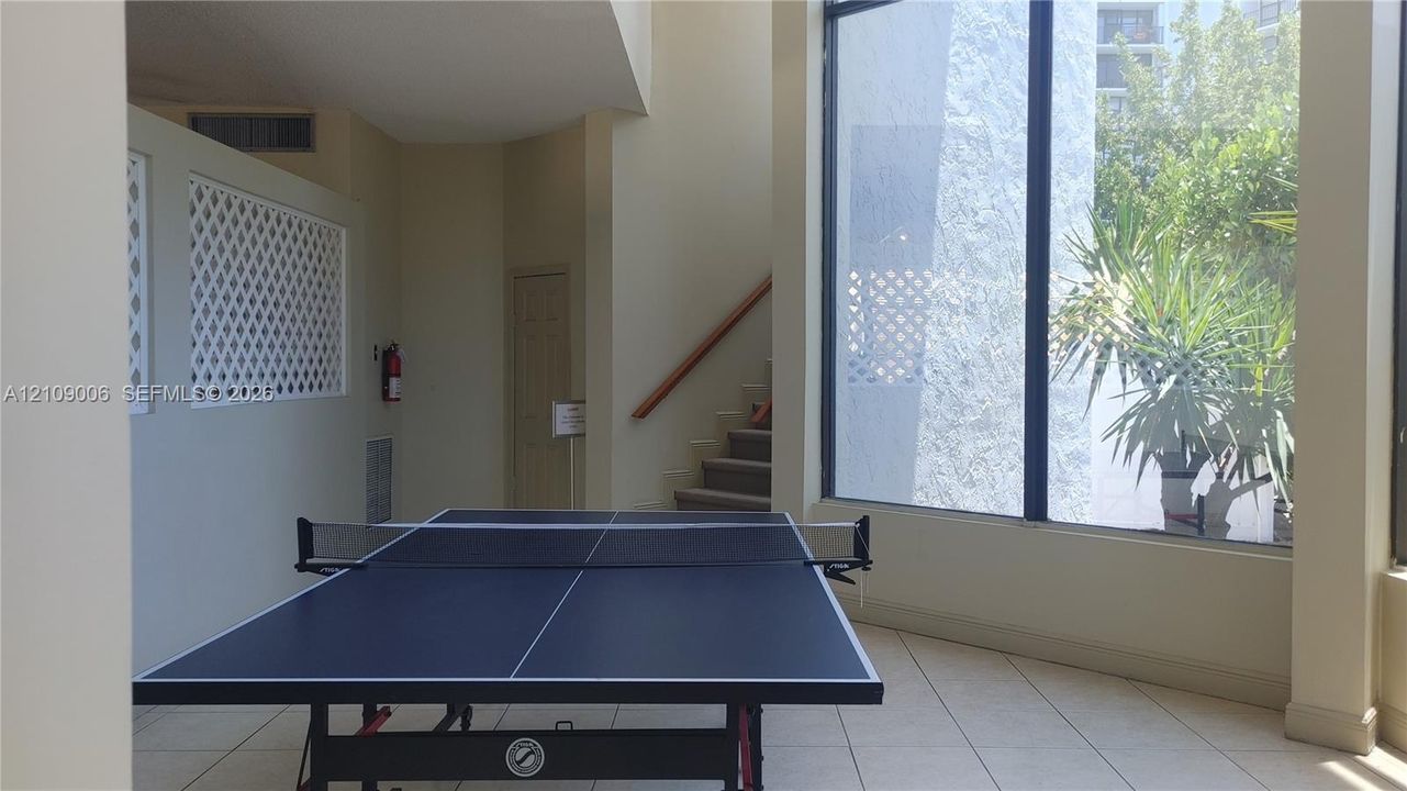 High-ceilinged room featuring floor-to-ceiling windows, tile flooring, and architectural lattice wall detailing