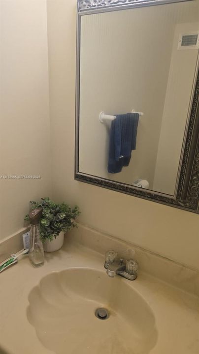 Wall-mounted mirror with decorative metallic frame, integrated countertop sink, and dual-knob faucet