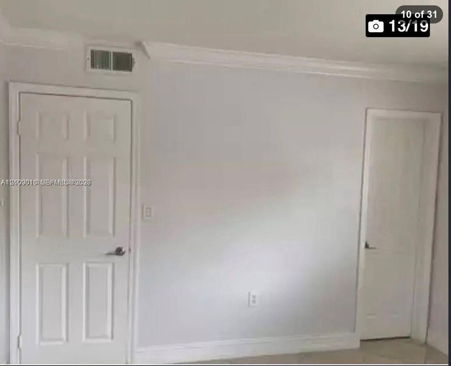 Neutral-toned interior featuring six-panel doors, crown molding, and stone-finish flooring