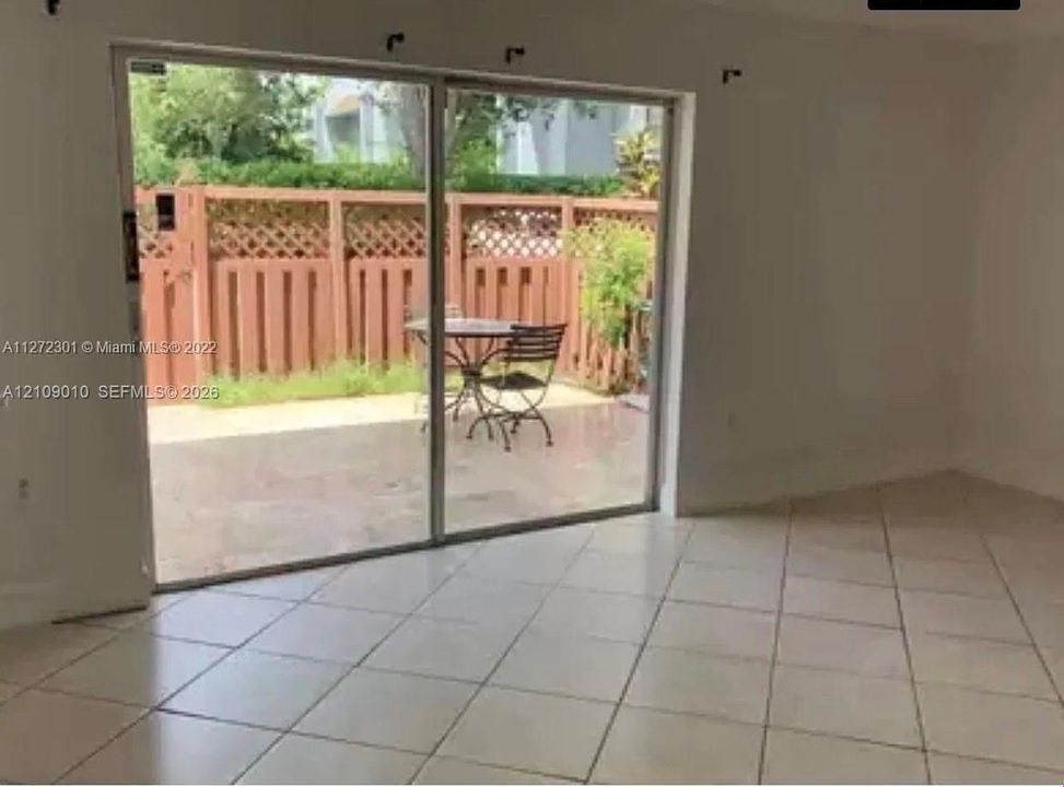 Sliding glass doors opening to a private exterior patio enclosed by wood lattice fencing