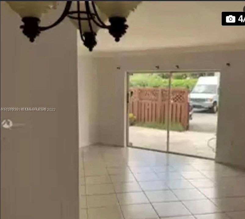 Ceramic tile flooring, sliding glass door, and multi-arm chandelier with glass globes