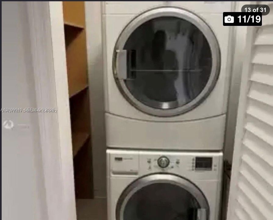 Laundry closet featuring a stackable washer and dryer unit and built-in wooden shelving