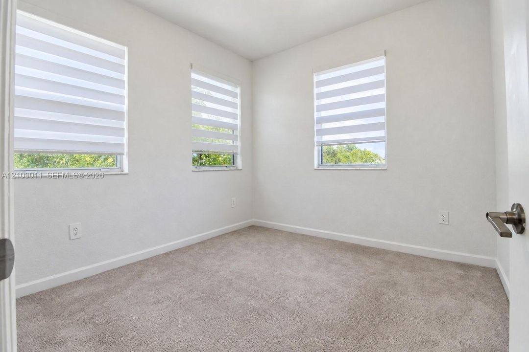 Neutral-toned carpeting, three windows with adjustable dual-layer shades, and minimalist interior trim