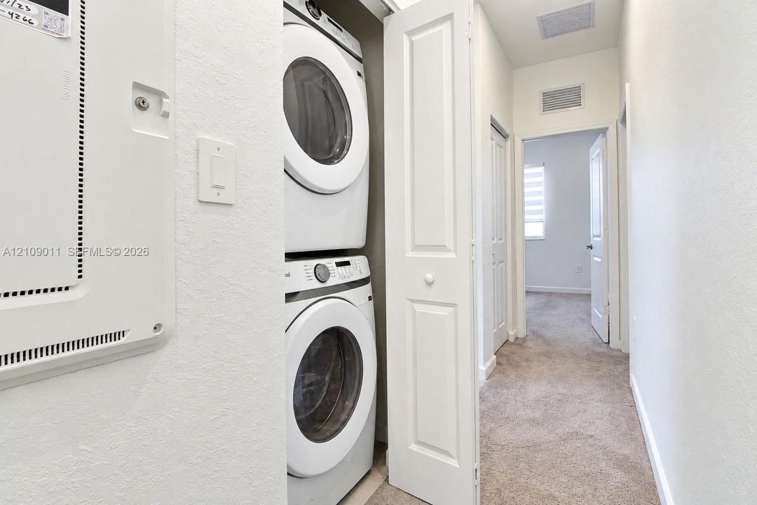 Laundry area featuring a stacked washer and dryer unit enclosed by bi-fold doors
