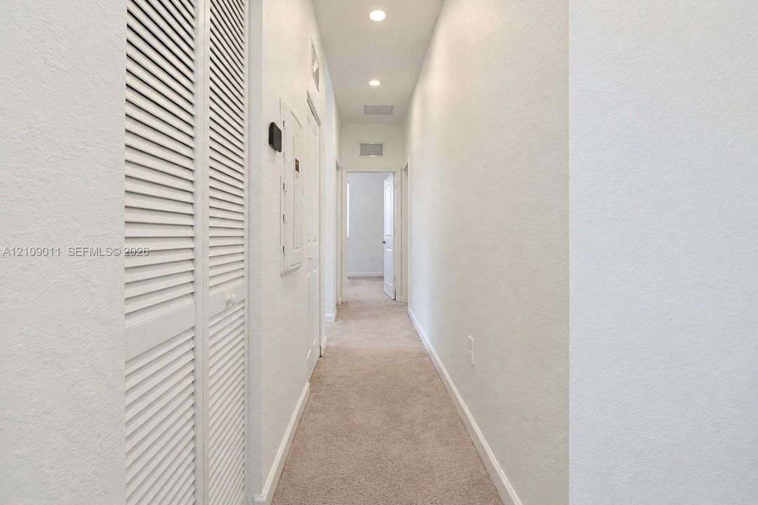Hallway featuring neutral carpeting, recessed ceiling lighting, and double bi-fold closet doors